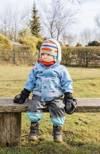 Cute baby girl wearing warm clothing while sitting on bench during winter