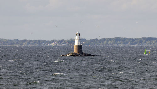 Lighthouse by sea against sky