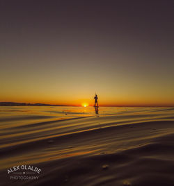 Silhouette person on beach against sky during sunset