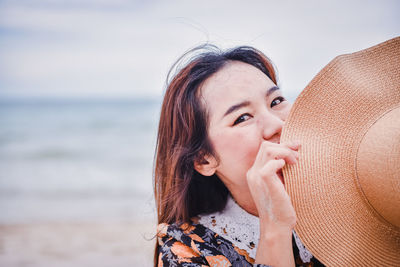 Portrait of beautiful woman wearing hat at beach