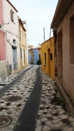 Cobblestone street amidst buildings against sky