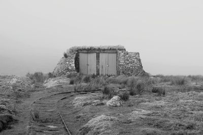 Abandoned built structure on field against clear sky