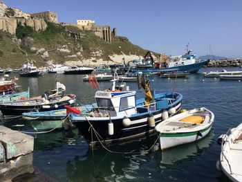 Boats moored at harbor against clear sky