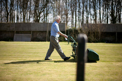 Side view full length of man mowing lawn