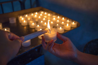 Close-up of hand holding lit candles