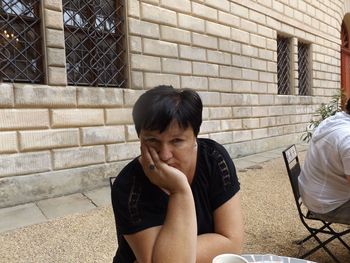 Full length of young woman sitting against wall