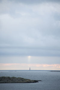 Light from the sky above a lighthouse on a gloomy day by the ocean