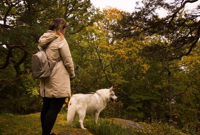Woman standing with dog at forest