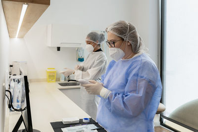 Female medical workers with protective face masks while preparing for medical procedure in hospital