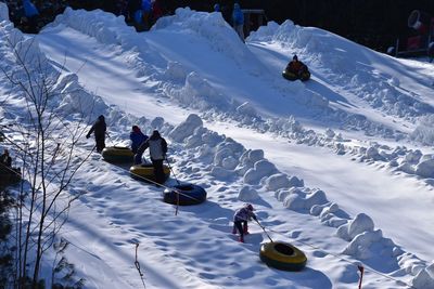 People pulling inflatable rings on snowcapped mountain