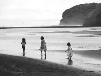 Children playing on beach against sea