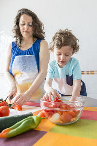 Woman preparing food while standing with son