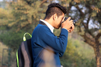 Side view of young man photographing through camera