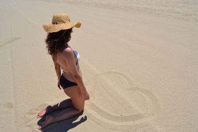 Woman in bikini kneeling at beach