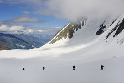 People hiking on snowcapped mountain against sky