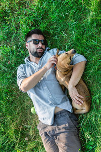 Top view of man and dog lying on green grass. attractive european man is hugging his dog.