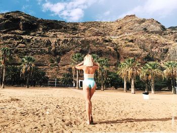 Rear view of woman standing on beach against sky