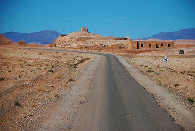 Road amidst desert against blue sky