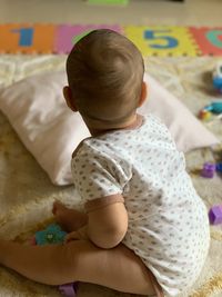 Rear view of a baby girl lying on bed