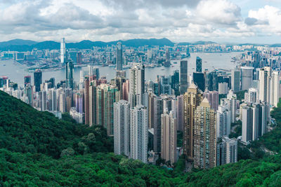 Cityscape and river against cloudy sky