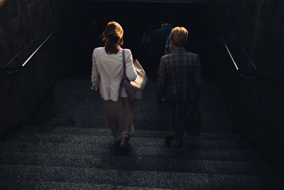 Rear view of women walking on staircase in city