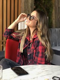 Smiling woman wearing sunglasses while sitting at cafe