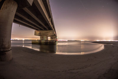 Suspension bridge over sea against sky at night