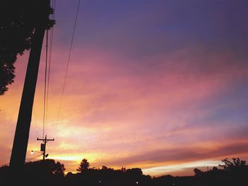 Low angle view of silhouette electricity pylon against romantic sky