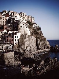 Buildings by sea against clear sky