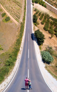 Rear view of couple standing on country road during sunny day