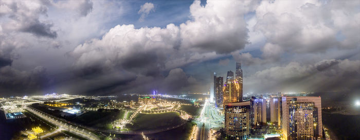 Panoramic view of illuminated buildings against cloudy sky