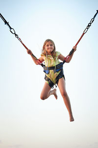 Full length of boy swinging against clear sky