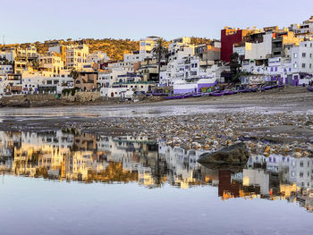 Buildings by river in town against sky