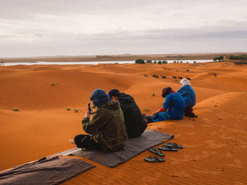 People sitting on sand dune in desert