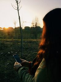 Rear view of woman using mobile phone in field