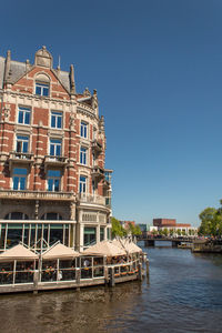 Building by canal against clear sky