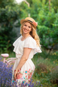 Portrait of young woman standing against trees