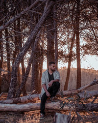 Full length of young man sitting in forest