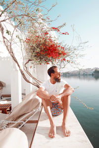 Full length of man sitting on retaining wall