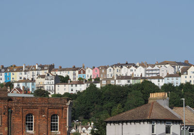 Buildings in city against clear blue sky