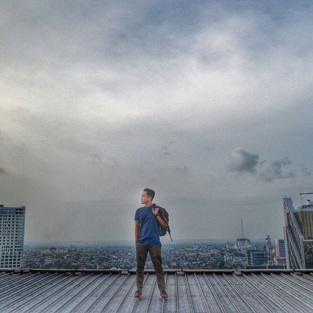 sky, full length, rear view, standing, lifestyles, casual clothing, cloud - sky, leisure activity, building exterior, built structure, architecture, cloudy, three quarter length, water, railing, cloud, men, sea