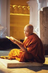 Monk reading book while sitting in temple