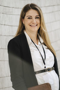 Portrait of smiling pregnant businesswoman standing at convention center