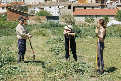 Farmers discussing at field on sunny day