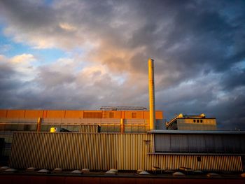 Low angle view of yellow factory against sky