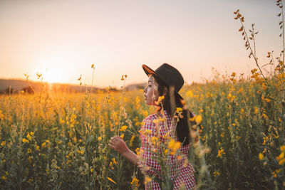 Young woman standing amidst yellow flowers