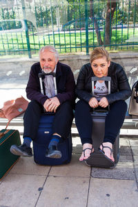 Portrait of young woman sitting on wall