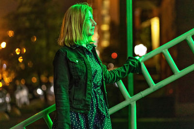 Portrait of a young woman in a night city in neon green on a summer evening. city lights.