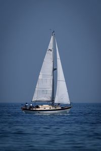 Sailboat sailing on sea against clear sky