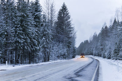 Car drives on empty snowy road in winter forest. beautiful frosty white landscape at dawn.